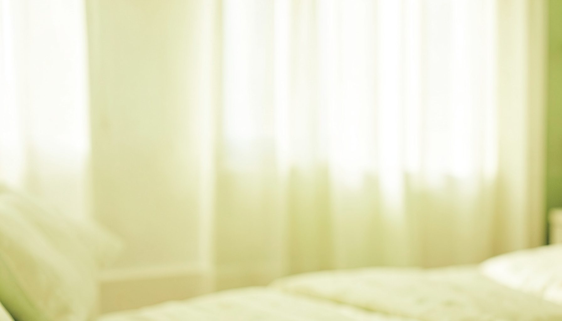 Soft, high-key indoor scene with warm cream and pale olive tones, blurred bedroom light streaming through sheer curtains, an airy and quiet mood with no visible people